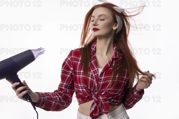 A fashionable woman enjoys drying her hair with a blow dryer, capturing a moment of style and beauty