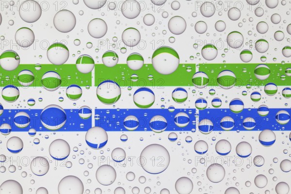 Flags of Sierra Leone behind a glass covered with raindrops. 3D illustration