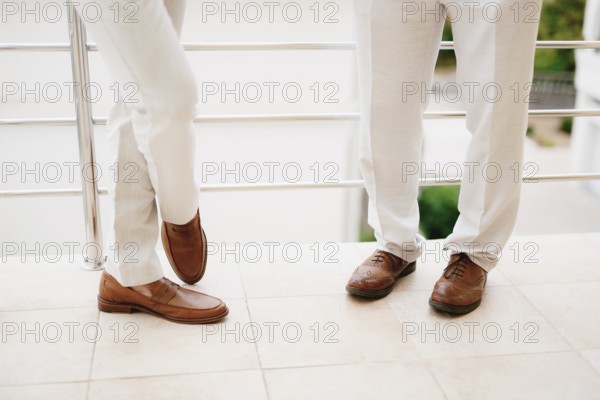 The legs of two men standing on the balcony, close-up. The groom and his best man during the preparation for the wedding ceremony. .