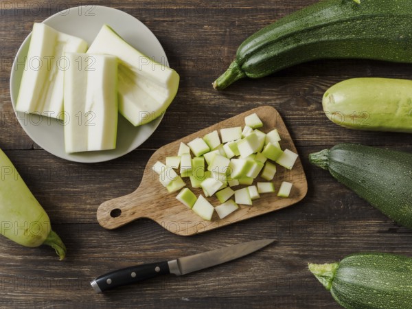 Zucchini harvest. Slices farm organic zucchini cubes for freezing on woodencutting board over brown wooden table. Zucchini harvesting concept. Top view or flat lay