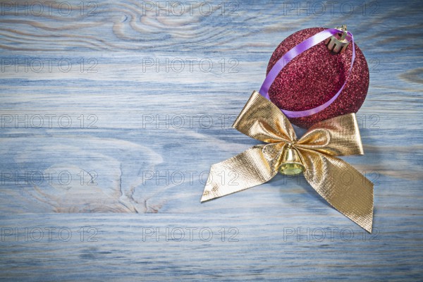 Red Christmas ball golden bow on wooden board holidays concept