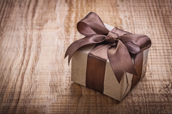 Single square vintage gift box qith brown bow on old wooden board