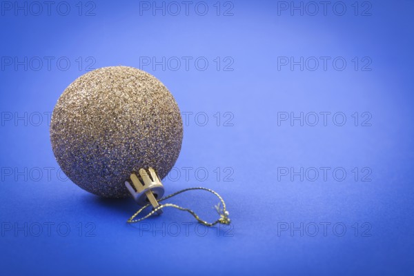 Single gold colored christmas ball on blue background
