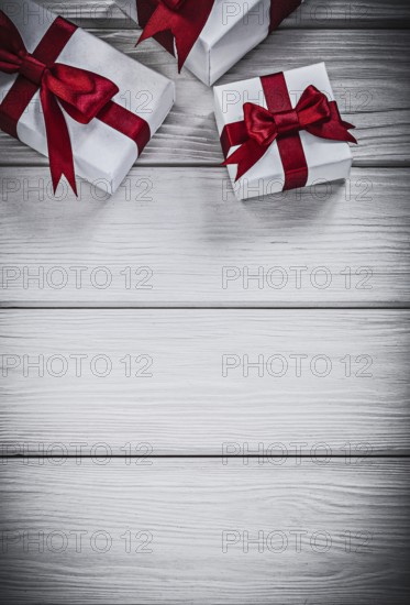 Present boxes with red ribbons on wooden board holidays concept