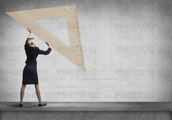 Woman holding big ruler on wall background. Testing and examination concept. Businesswoman measuring something with ruler. Human resources recruitment. Creative motivation, coaching and mentoring