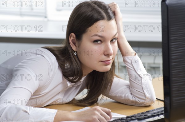 Attractive young caucasian brunette businesswoman sitting in her office