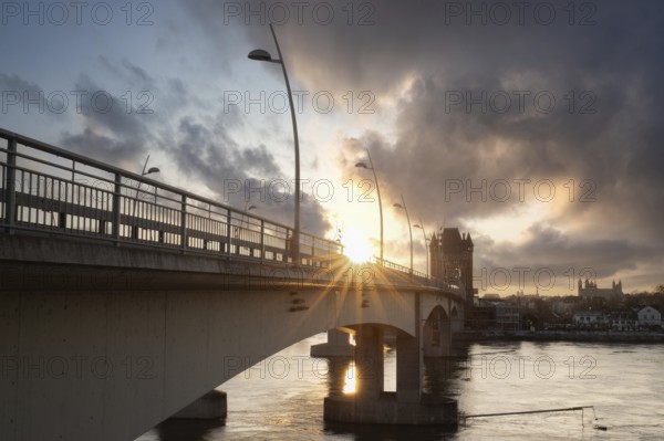 A road or motorway leads through an old historic city gate. Sunset in the evening over the Rhine near Worms, Germany, Europe