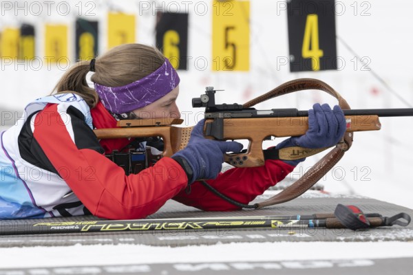Russian sportswoman biathlete Vakhrusheva Valentina rifle shooting in prone position. Biathlete in shooting range. Open regional junior biathlon competitions East Cup. Kamchatka, Russia, Apr 12, 2019, Europe