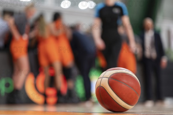The ball lying on the parquet and the basketball team in the background.
