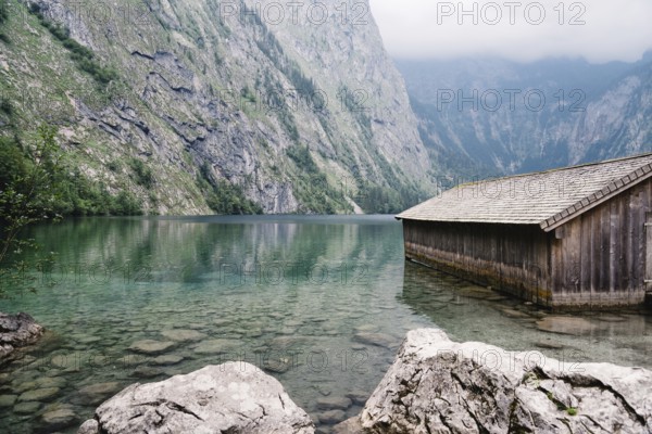 Wooden cottage in beautiful lake in the Alps with misty mood