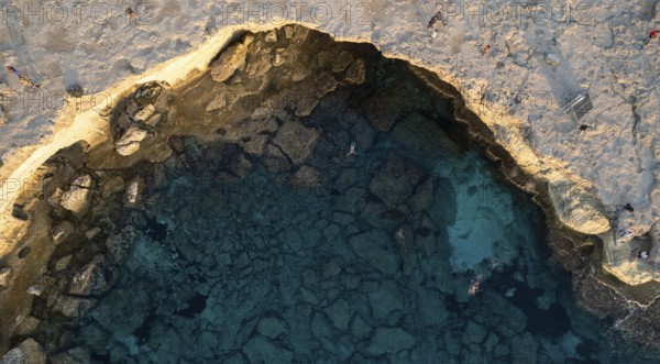 Drone aerial of unrecognized people swimming in the sea. Summer holidays. People active outdoors. Sea caves cape greco Cyprus