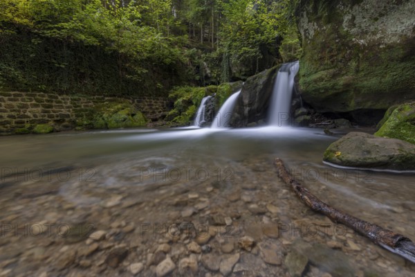 Cascade shooting pond, waterfall under small pedestrian bridge, Mullerthal Trail, Waldbillig, Luxembourg, Europe