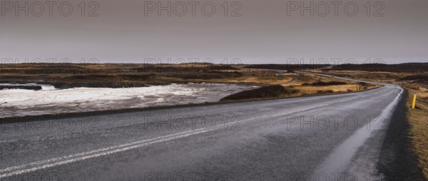 Empty asphalt motorway main road with icy frozen lake in Iceland