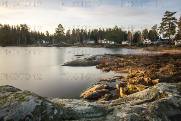 Shore of a lake at sunrise. Landscape shot in Narur in the morning. Forests, lake and water at the beginning of winter or in autumn. Sweden, Scandinavia
