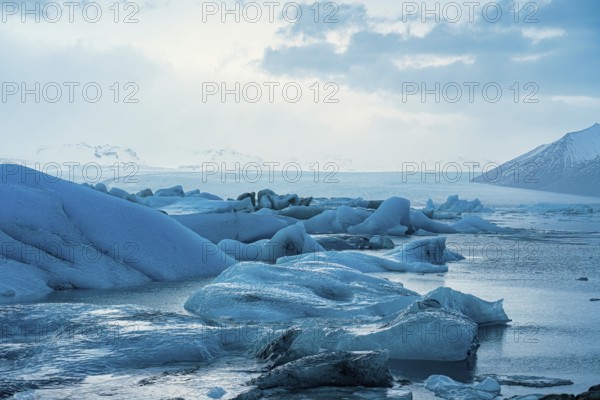 Expansive view of ice floes with mountains and ocean under a clearing sky, iceberg Iceland, glacier, snow, ice rock, ice diamont, glacier lagoon, nature, snow, diamont beach, Iceland, Europe