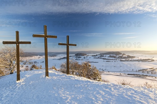 Three summit crosses on a mountain peak in a beautiful winter landscape in the Swabian Alps at sunset