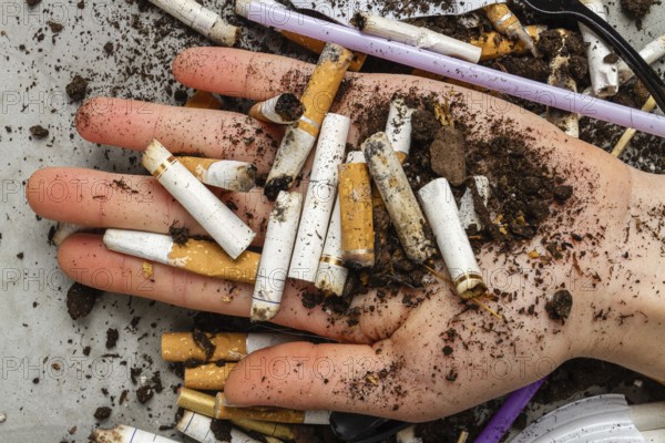 Close up hand holding pile of cigarettes with dirt. Concept of enviroment pollution