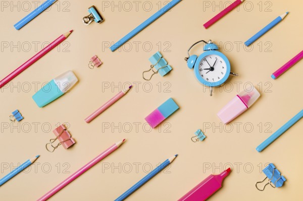 Creative student desk modern school supplies on neutral pastel beige background. Top view flat lay. Back to school concept. Diagonal pattern with pencils, pens, markers, alarm clock, stationery clips
