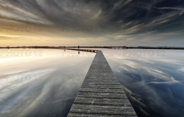 Wooden path on water on big lake before sunset