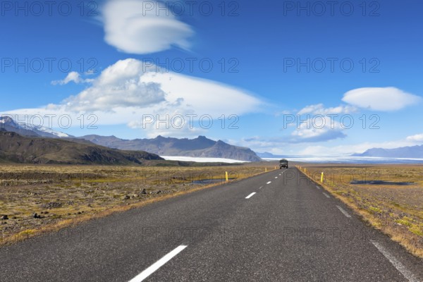 Highway through South Icelandic landscape under a blue summer sky with clouds