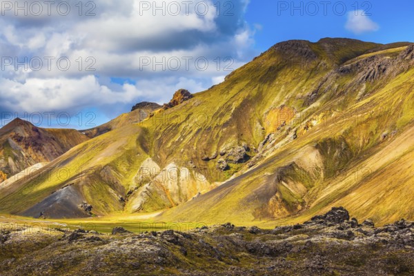 Travel to Iceland in the July. Summer volcanic tundra. Multi-colored mountains from mineral rhyolite are lit with sun