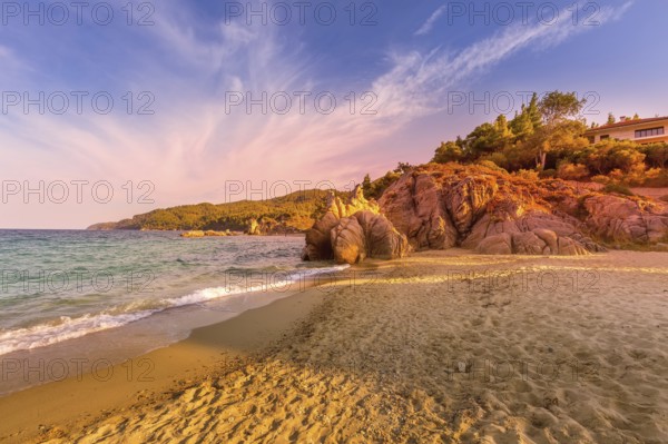 Vourvourou, Chalkidiki or Halkidiki, Greece summer sunset scenery with turquoise sea, forest green mountains and rocks at Fava sandy beach