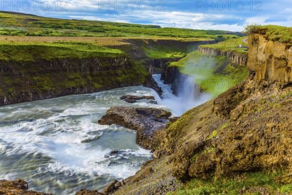 Tundra on a sunny summer day. The waterfall in Iceland - Gullfoss on the Hvitau River. Huge masses of water crash into a narrow gorge. The concept of extreme and phototourism