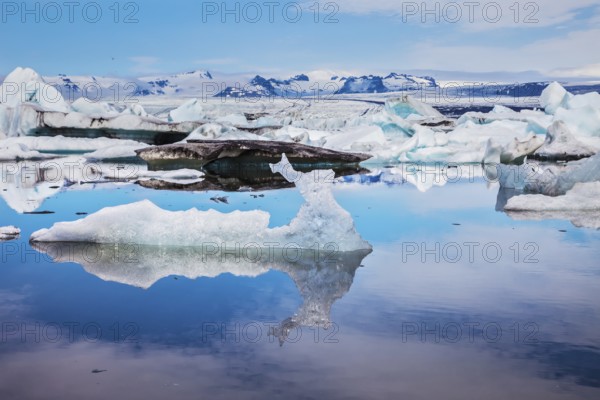 Ice lagoon in July. Ice floes and icebergs are reflected in the mirrored water of ocean. Summer vacation in Iceland