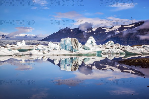Icebergs and ice floes are reflected in the smooth water surface. Drift ice Ice Lagoon - Jokulsarlon. Morning in the Iceland. The concept of extreme northern tourism