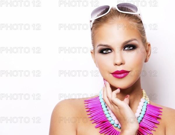 Beautiful woman with dark makeup and pink lipstick posing on white background wearing bright necklace and sunglasses, Toronto, Canada, North America