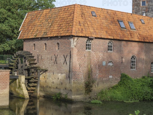 Detailed view of a brick watermill with water wheel and surrounding vegetation, winterswijk, gelderland, the netherlands