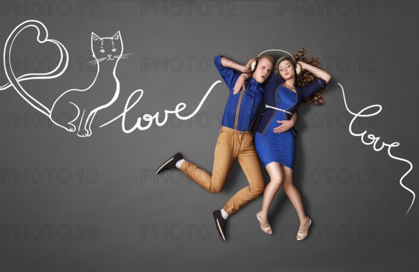 Happy valentines love story concept of a romantic couple sharing headphones and listening to music about love against chalk drawings background of lyrics