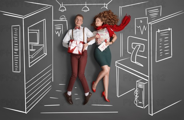 Happy valentines love story concept of an office romance. Young couple at work smiling at each other and exchanging gifts against chalk drawings office background