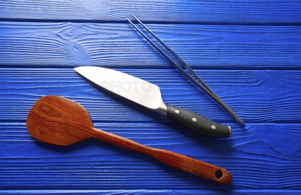 Chef tools knife tweezers and spatula on a blue wooden background