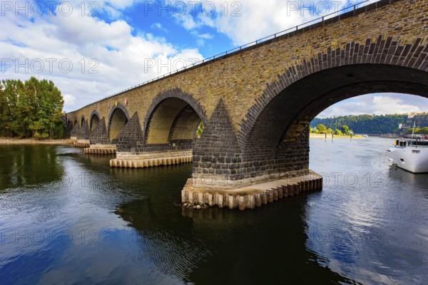 Pleasure boat. Romantic trip to medieval Germany. Scenic Baudouin bridge over the majestic river Moselle connects the Old Town with the Lützel district. Koblenz. Cloudy warm autumn day