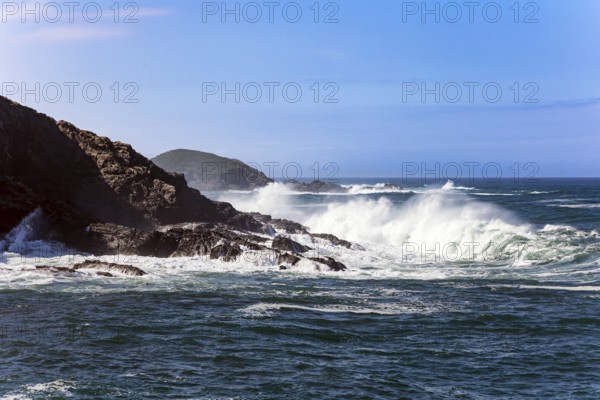 Huge waves of ocean surf beat against stone breakwaters. Magnificent Atlantic Ocean. Picturesque fishing port of the city of Luarca in the bay. Romantic trip to Spain. Asturias