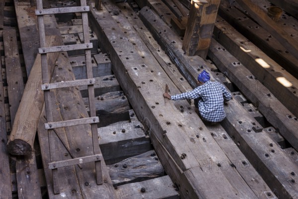 Shipbuilder working on a wooden boat under construction, Mandvi, Gujarat, India, Asia