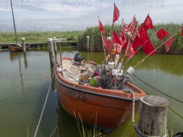 Red fishing boat with red flags and equipment in a quiet harbour, Zingst, baltic sea, germany