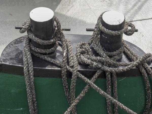 Close-up of two black metal bollards on a boat, surrounded by ropes and knots, carolinensiel, germany