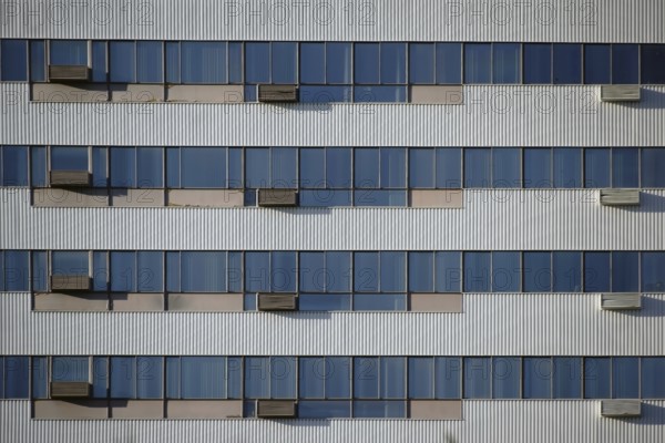 The modern façade and exterior wall of an office building with solar control windows and air conditioning systems
