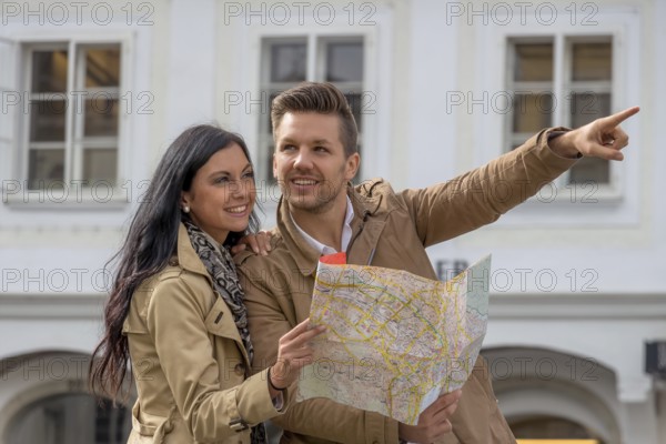 Young couple with city map and travel guide while visiting a city on holiday Austria