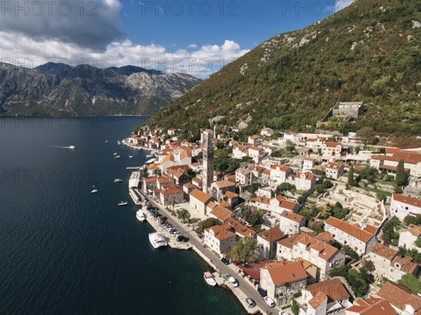 Cars parked on the promenade near the bell tower of the Church of St. Nicholas. Perast, Montenegro. Drone.