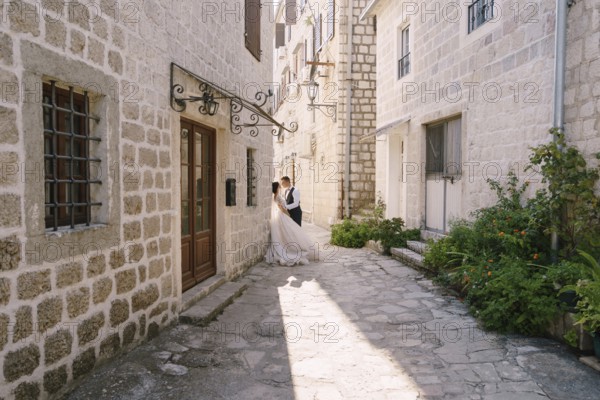 Wedding couple on the street of the old city, among ancient houses. Fine-art wedding photo in Montenegro, Perast