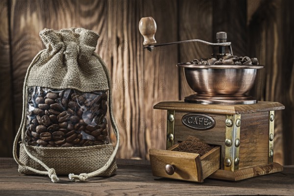 Vintage sack with coffee beans and wooden mill on wood background