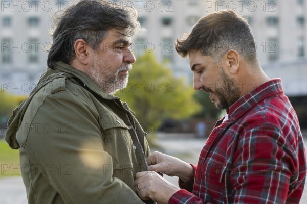 A man is adjusting his husband's jacket