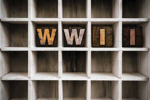 The word WWII written in vintage ink stained wooden letterpress type in a partitioned printer's drawer