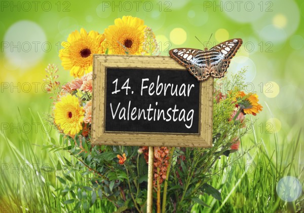 An image of a little chalkboard in the garden with the text 14th of february Valentines Day in german language