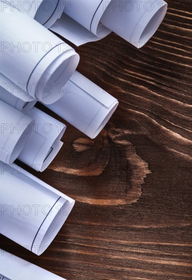 Rolls of construction plans on vintage wooden pine board maintenance concept