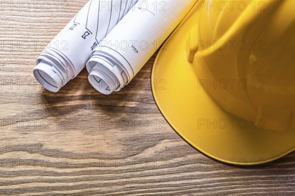 Rolled engineering drawings hard hat on wooden board construction concept