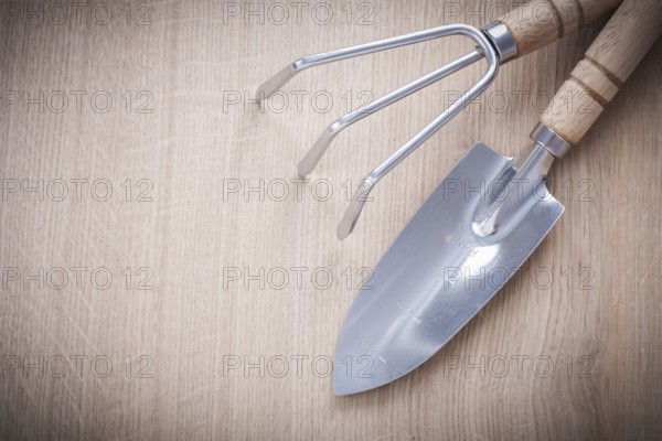 Stainless gardening trowel fork with sharp hand spade on wooden board horizontal version agriculture concept